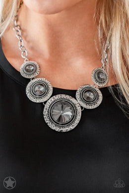 Gradually increasing in size, dramatically oversized smoky gems are pressed into the centers of hammered and silver studded frames. The blinding frames link below the collar for a glamorous, statement-making finish. Features an adjustable clasp closure.  Sold as one individual necklace. Includes one pair of matching earrings.